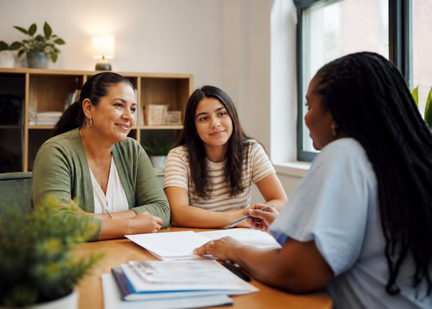 A parent and their teenage daughter meeting with a program team member across a table.